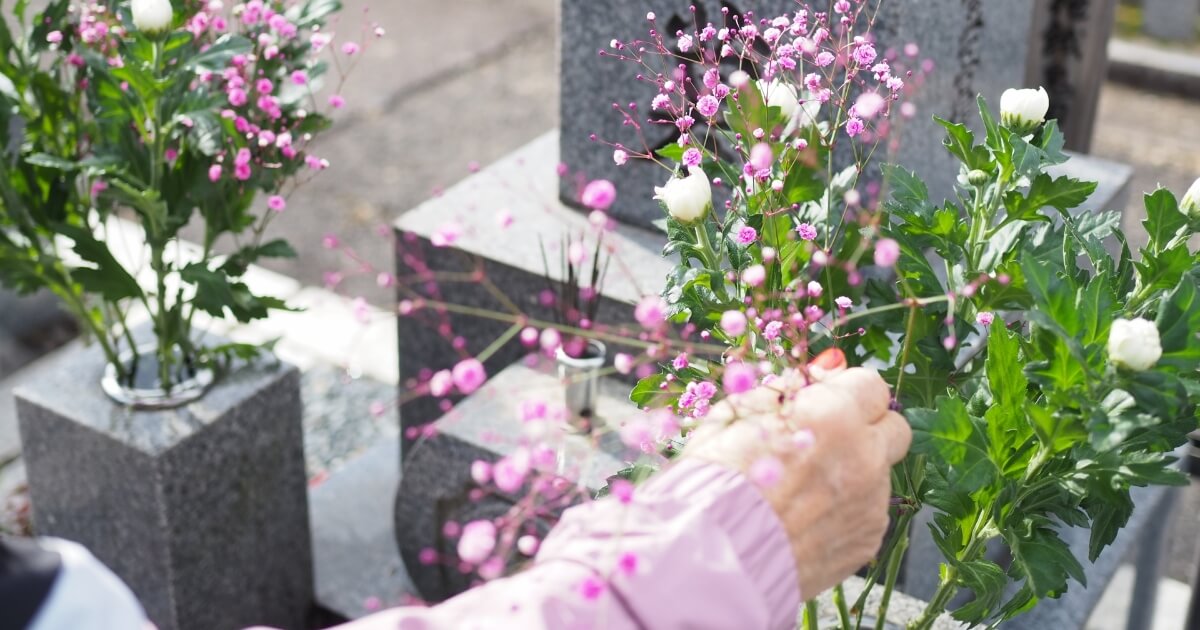 お墓と花と老女の手